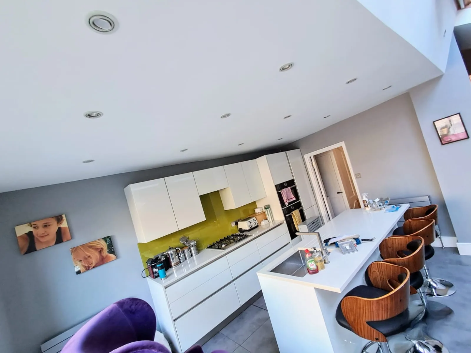 Modern kitchen with white cabinetry and green backsplash