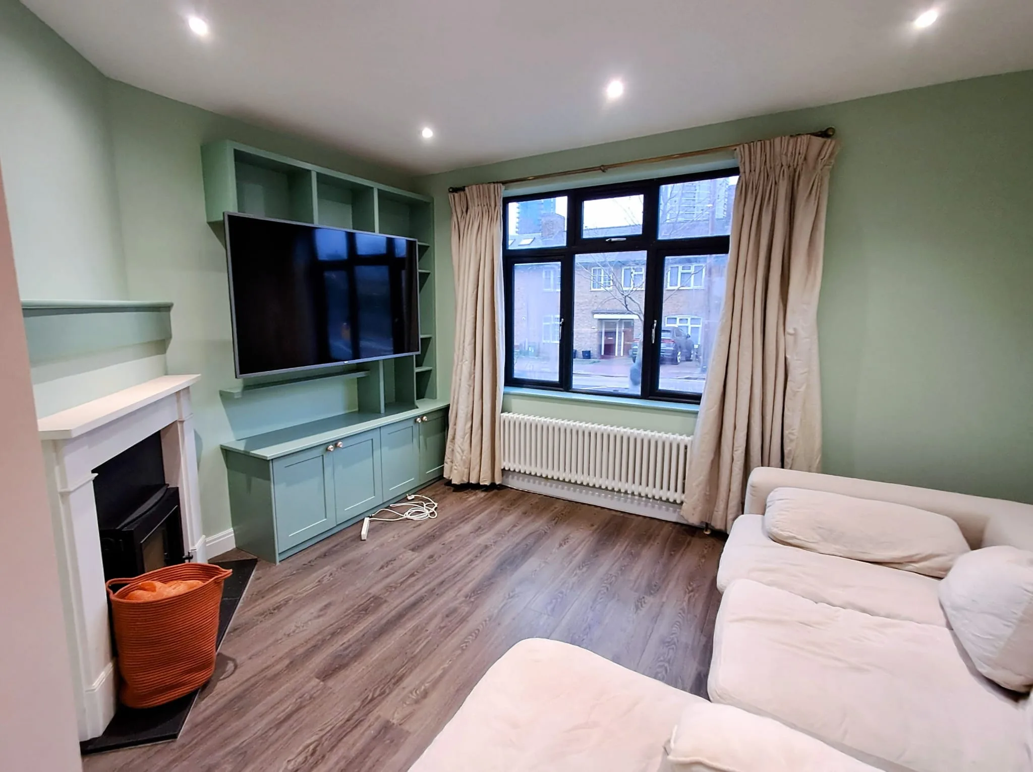 Modern living room with sage green walls and cabinetry
