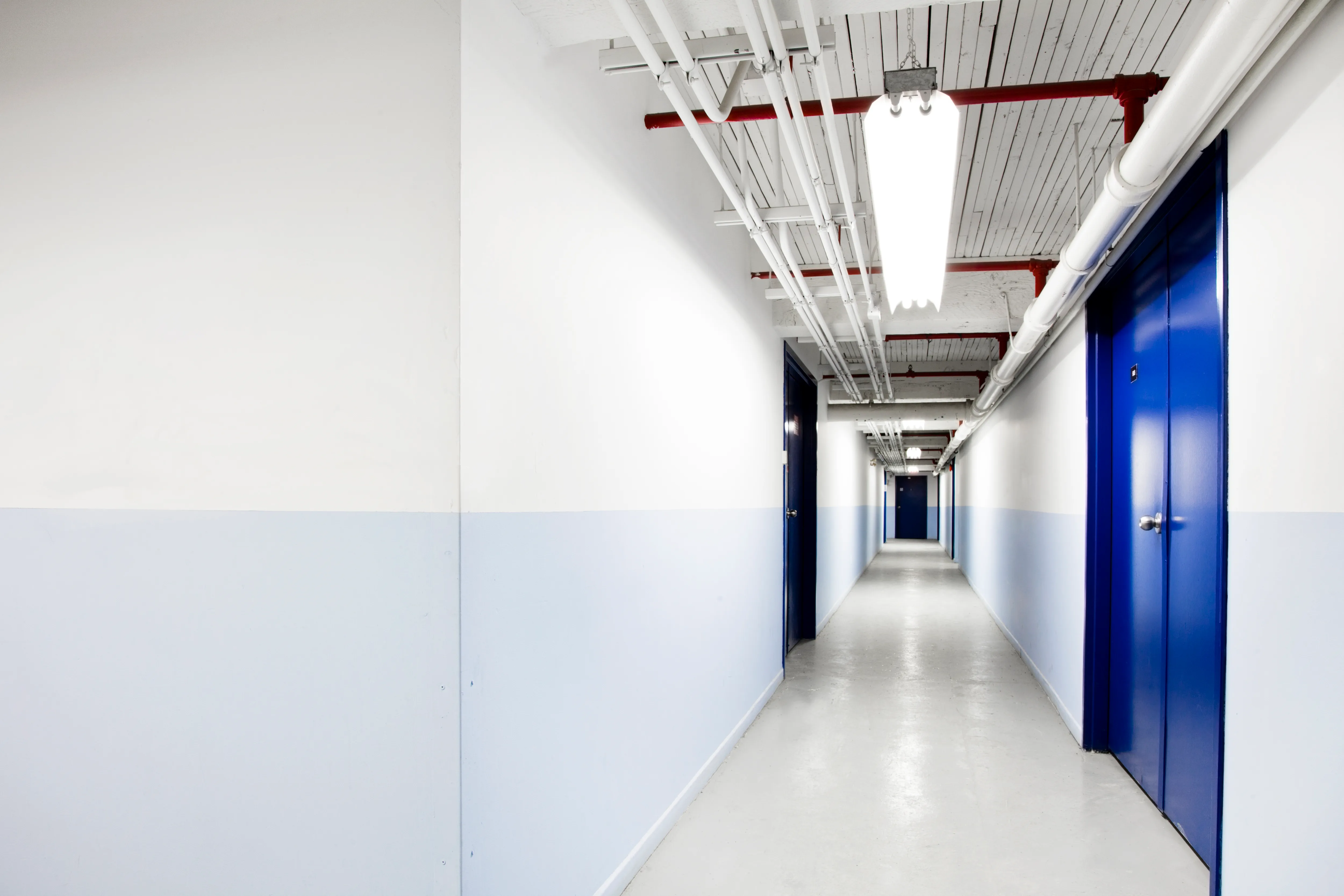 Brightly lit hallway with blue doors and light blue wall sections showcasing interior painting services