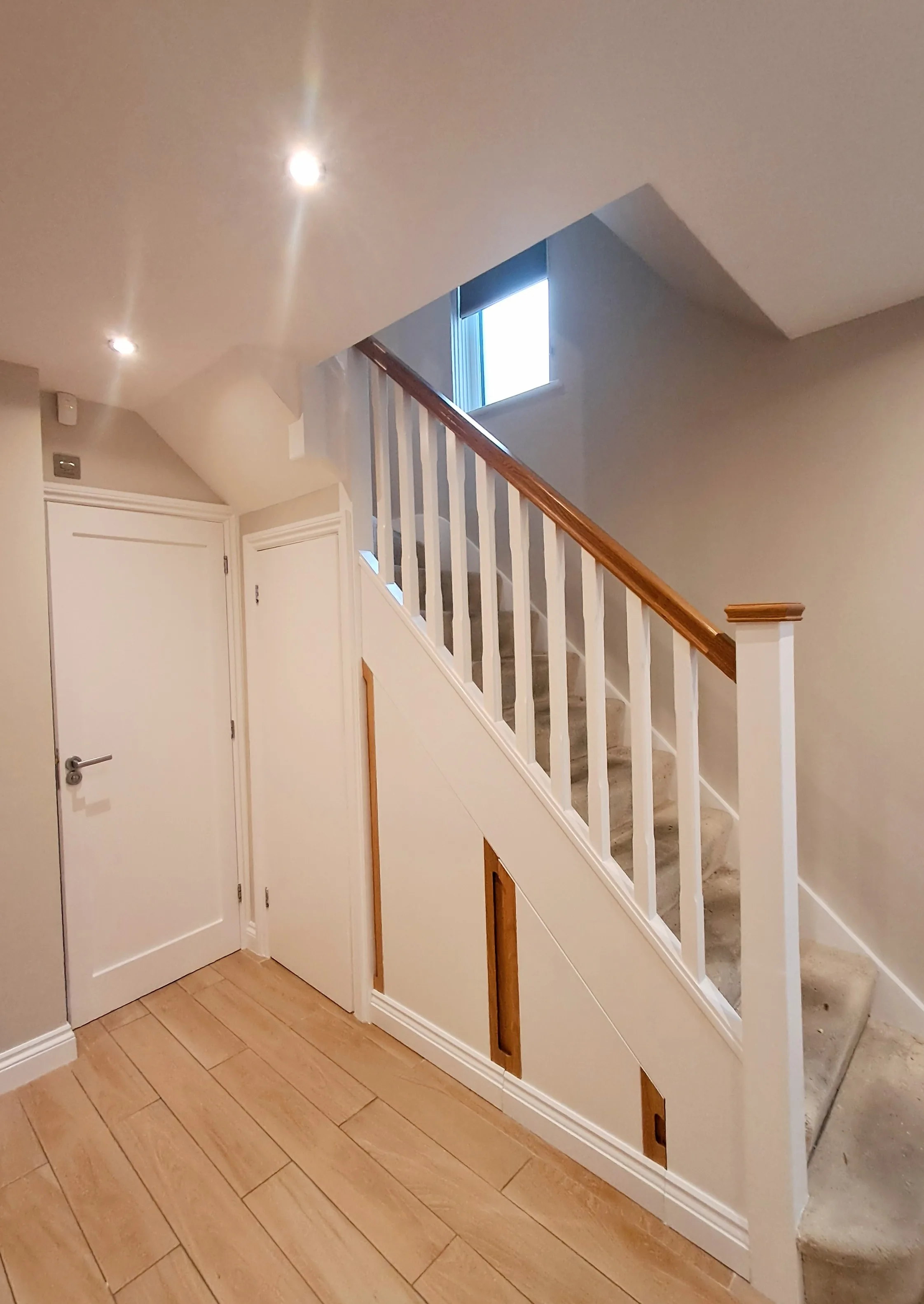 A well-lit interior staircase with wooden railing and beige walls, showcasing professional painting