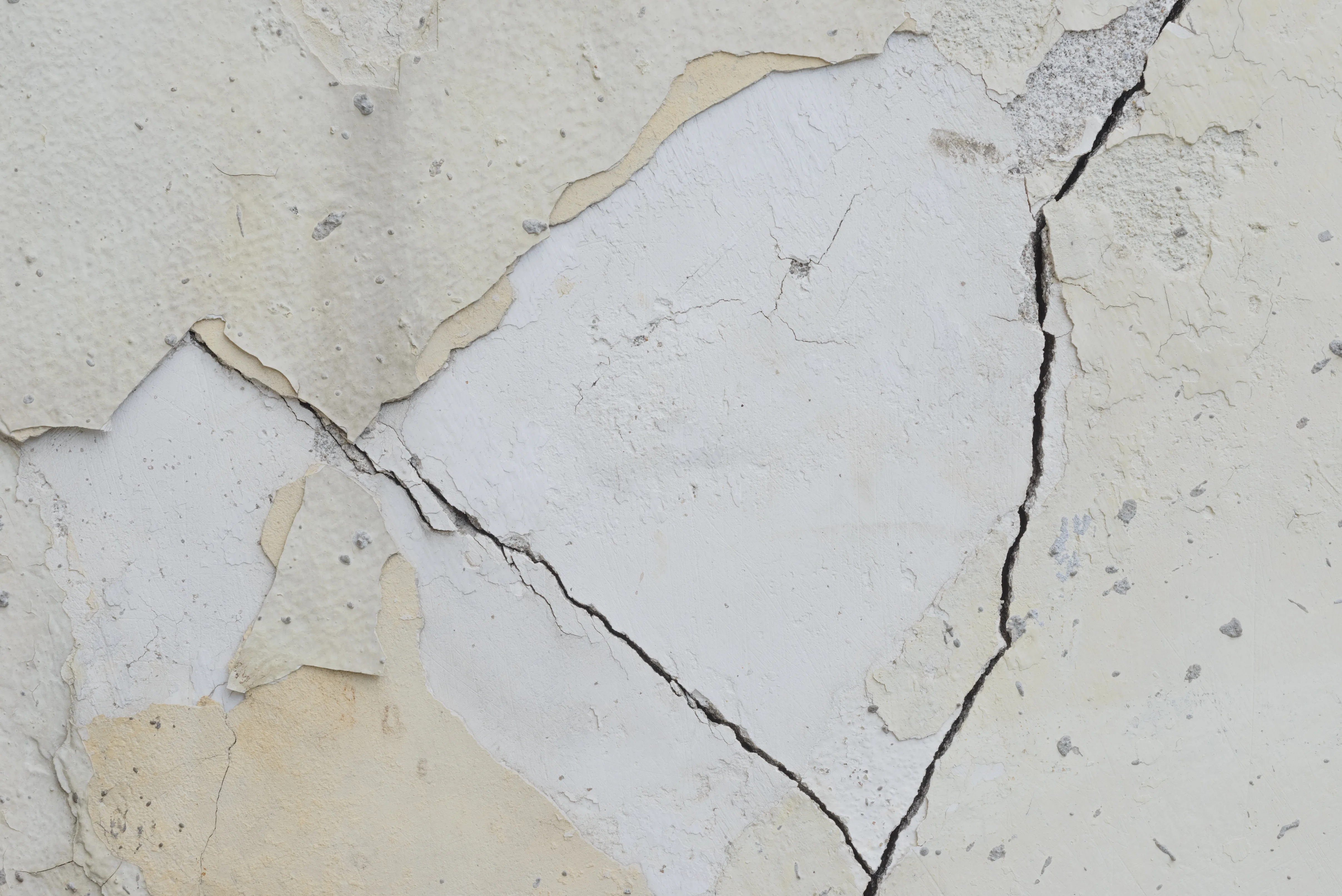 Close-up of cracked and peeling wall surface, indicating a need for wall repair services