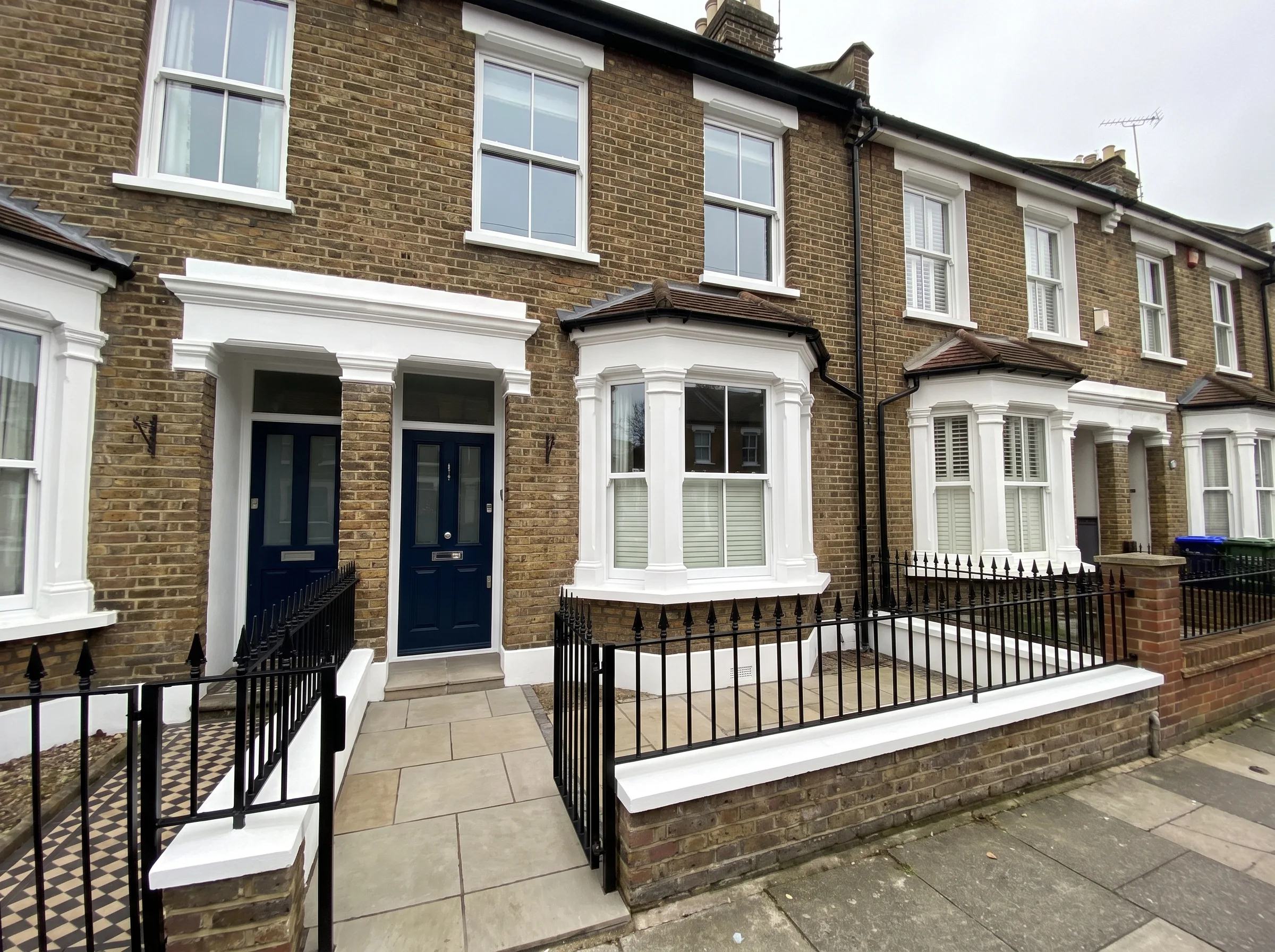 Front view of a beautifully painted townhouse with decorative woodwork and a clean facade
