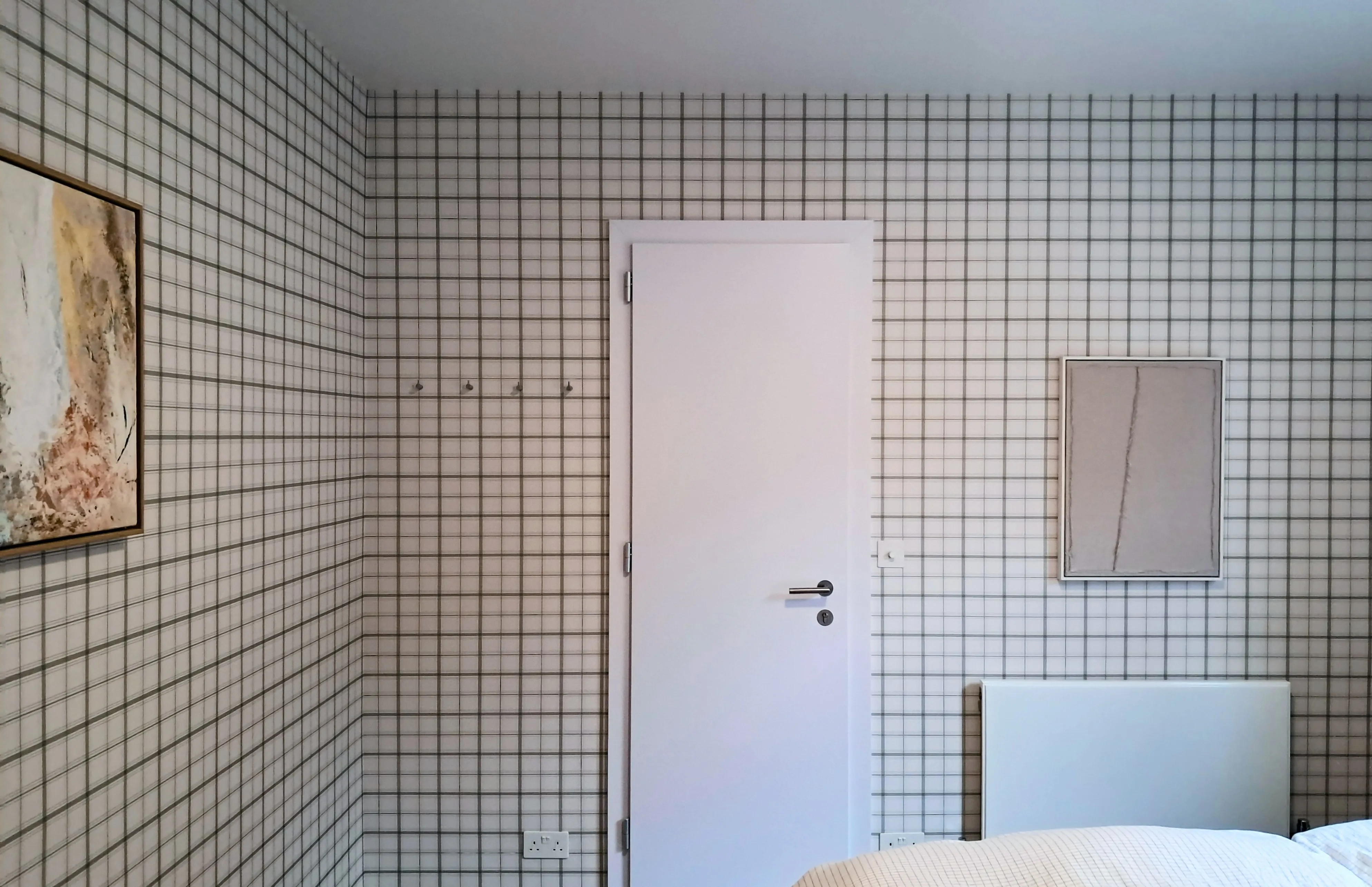 Interior wall with grid pattern wallpaper, white door, and minimal decor