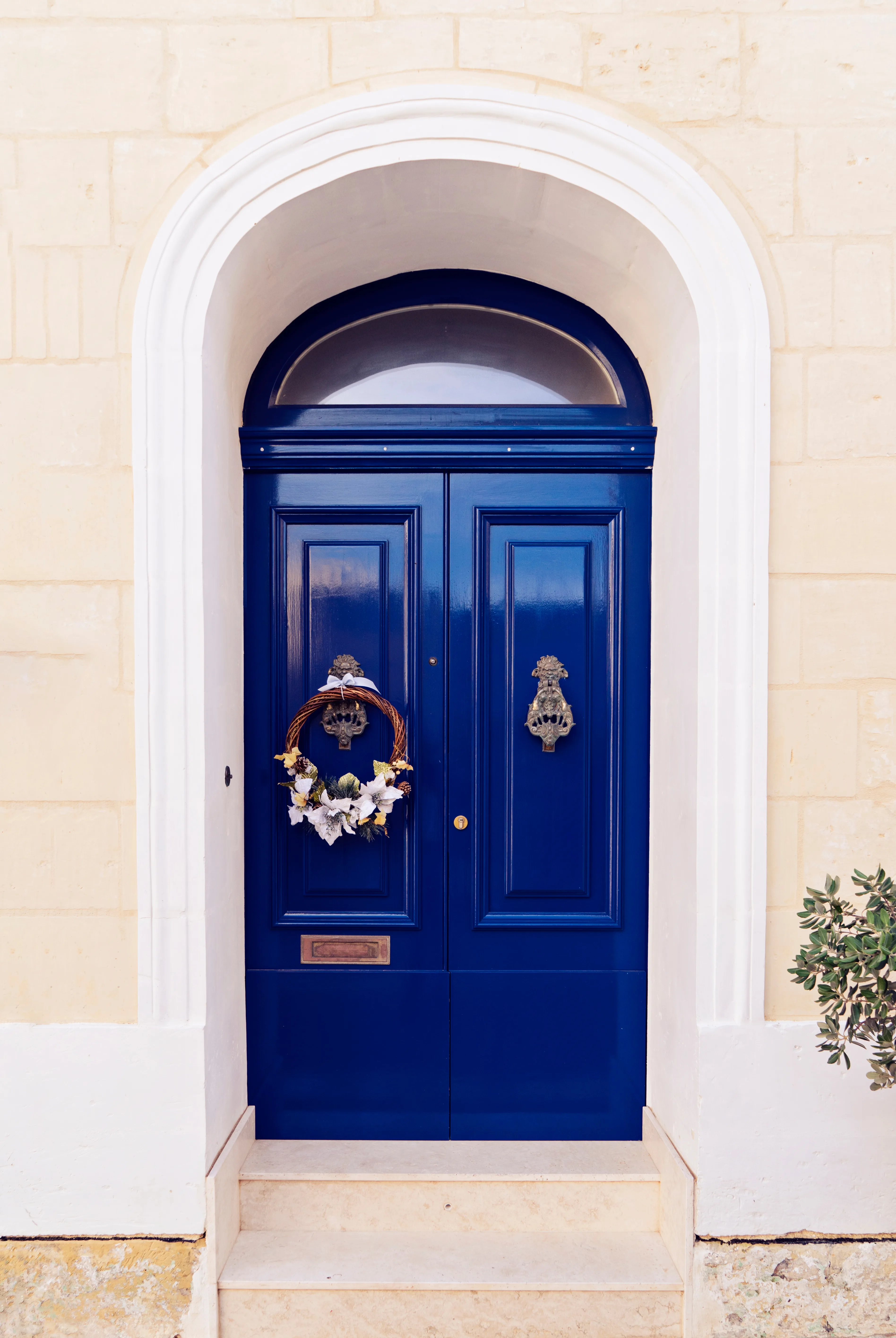 A freshly painted blue door adorned with a decorative wreath, showcasing exterior door painting