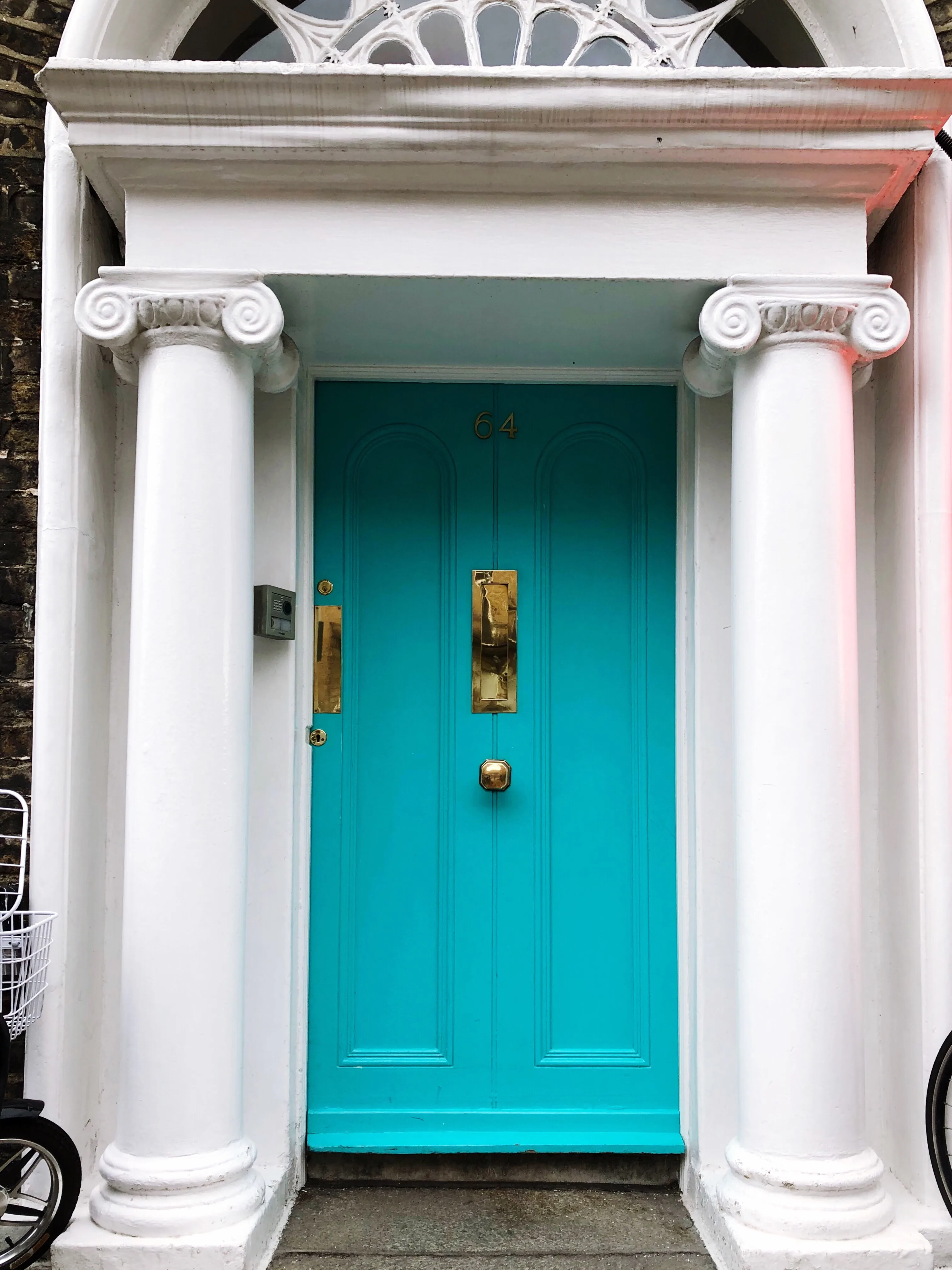 Bright turquoise door with white columns and decorative features, showcasing exterior door painting