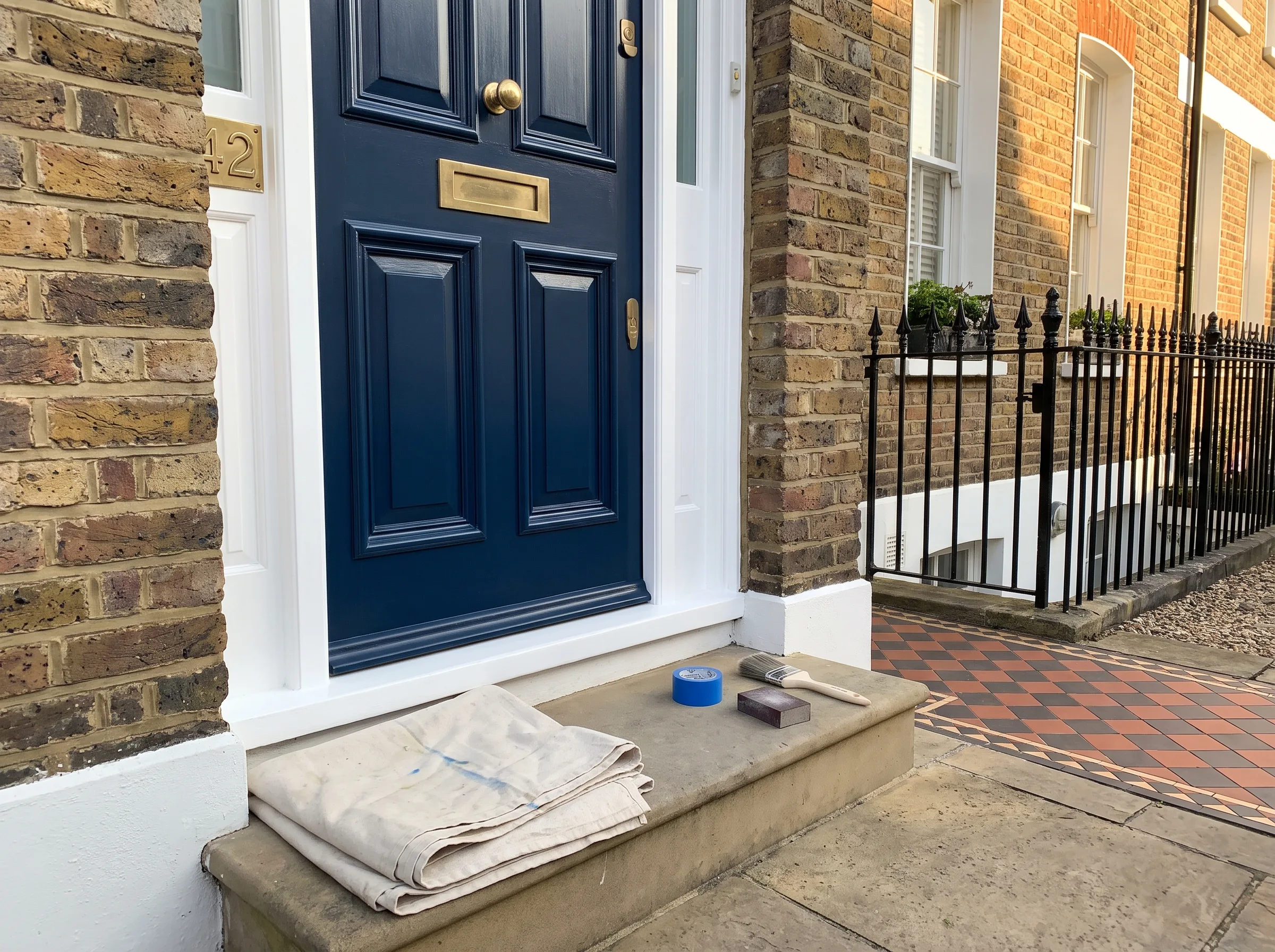 A freshly painted blue front door with a brush and tools on the steps, showcasing exterior door painting services