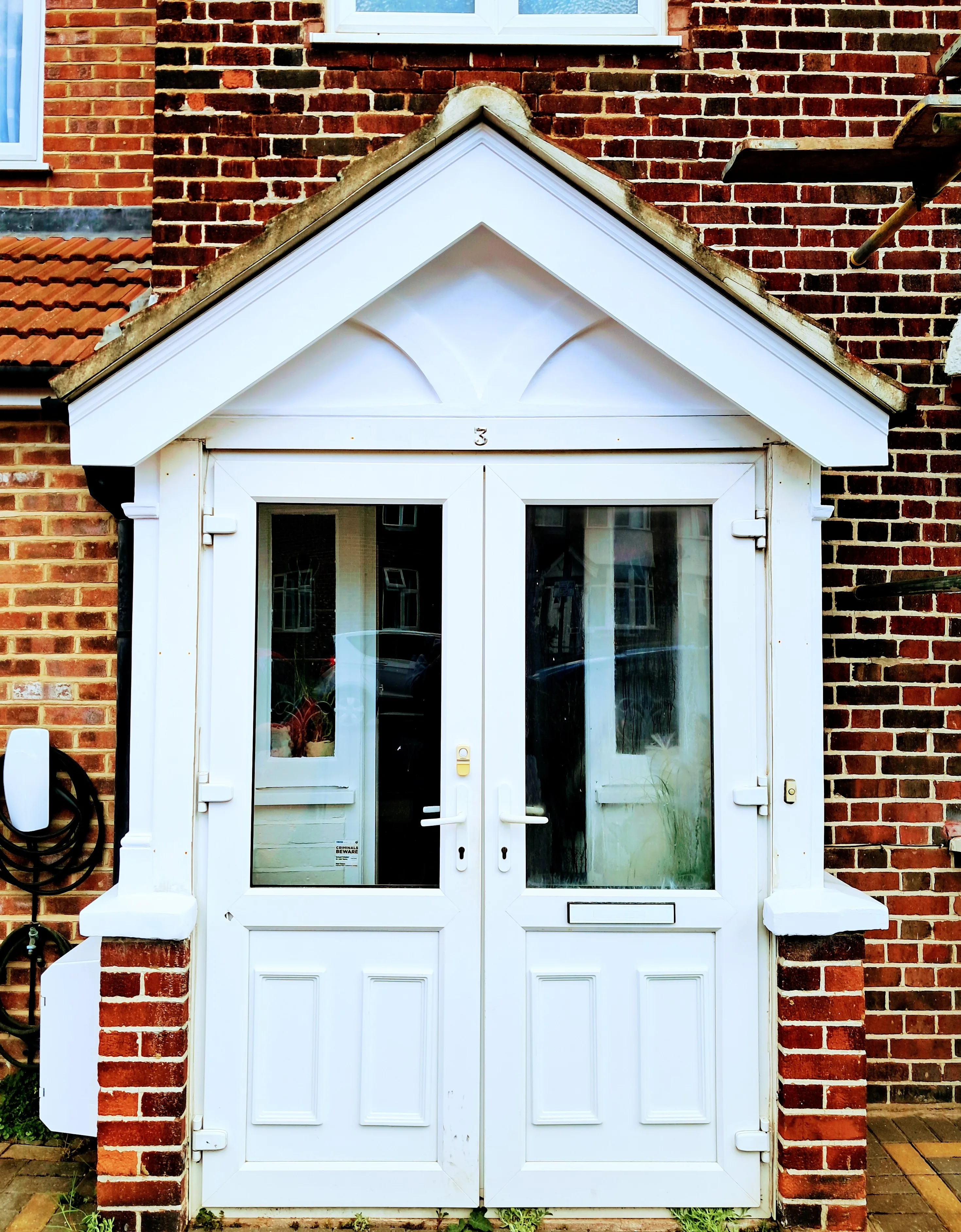 White double doors with decorative trim on a brick facade