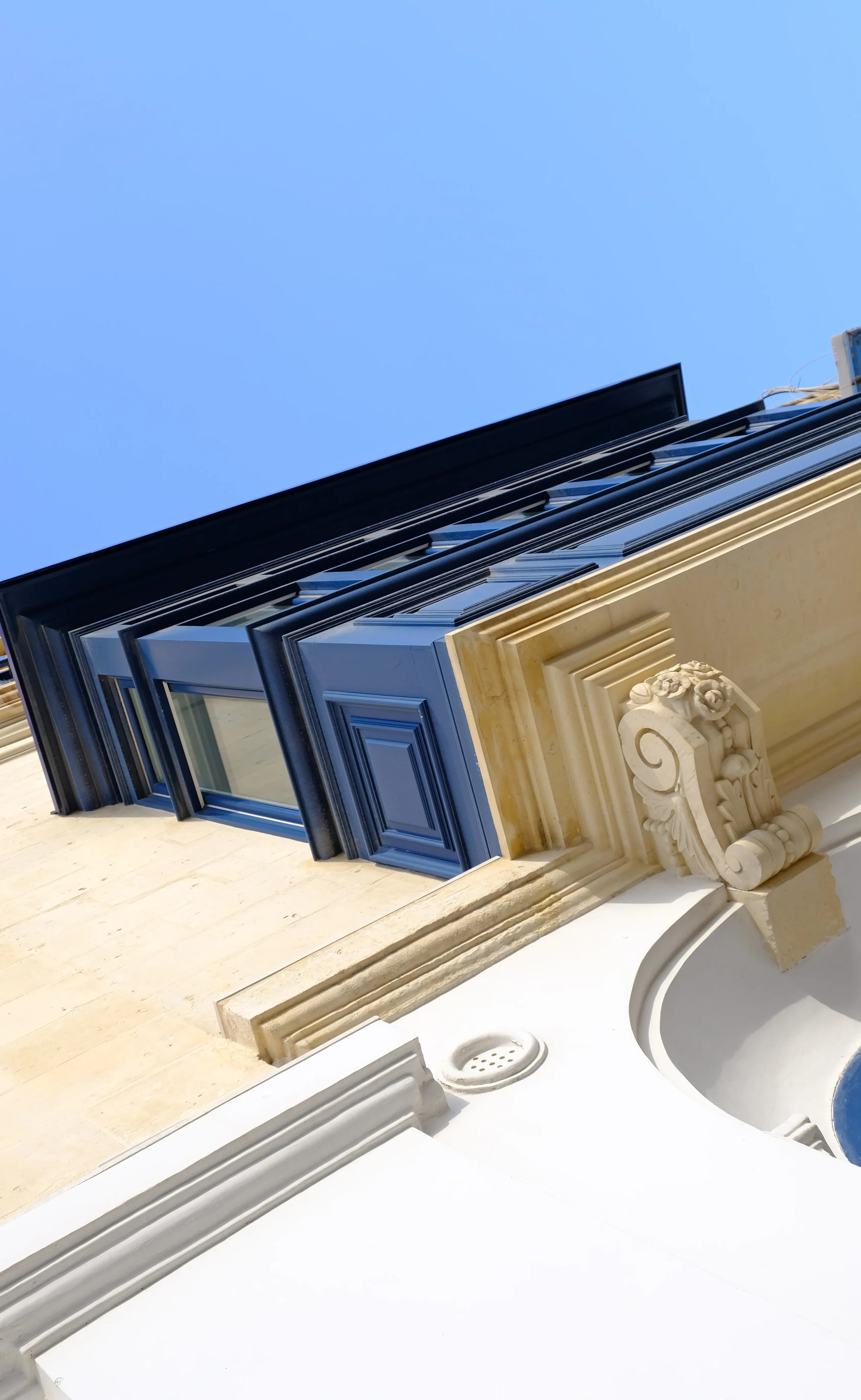 Close-up of a painted exterior balcony with decorative woodwork and blue accents against a clear sky