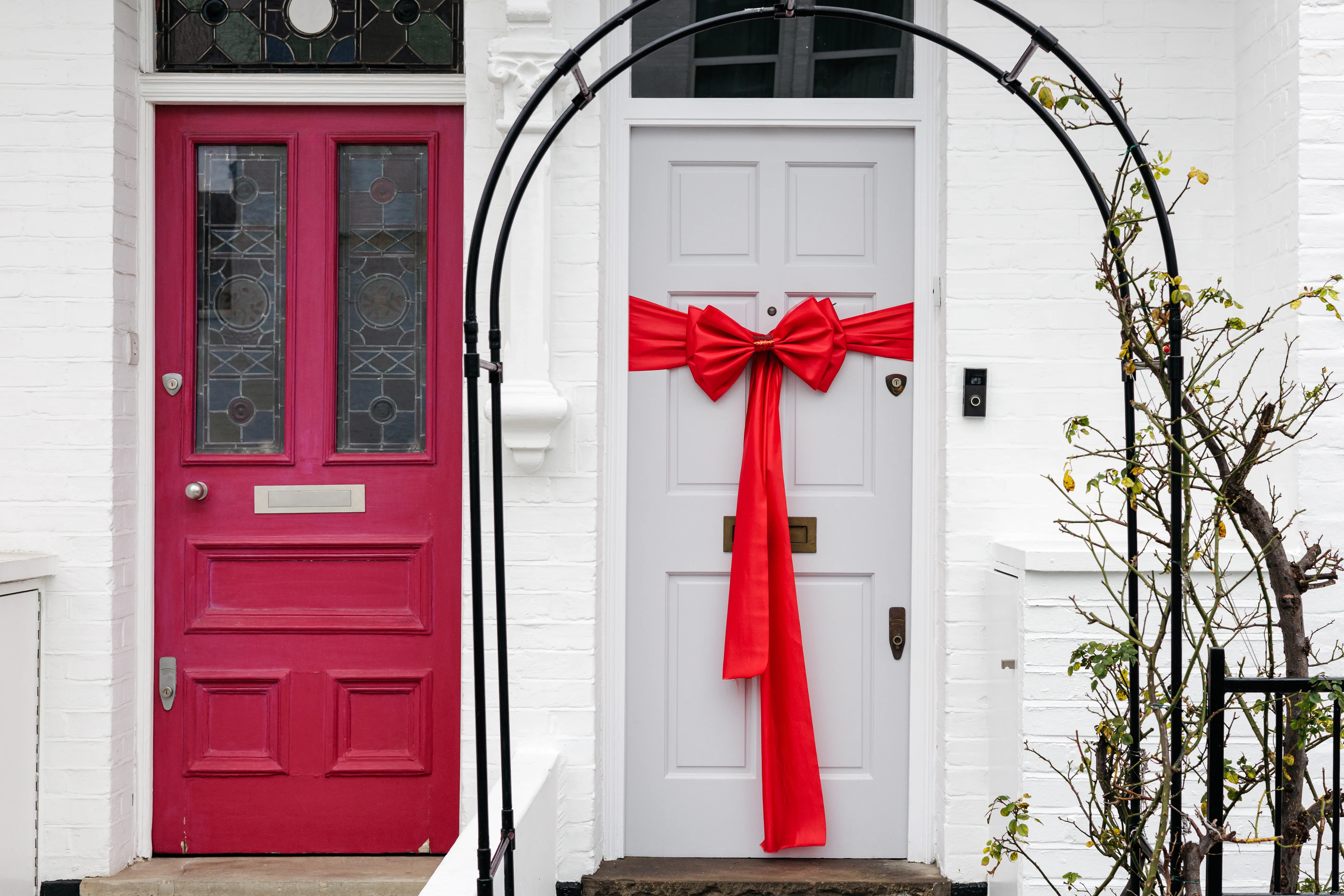 Two colorful doors adorned with a red bow on the white door, showcasing professional door decorating