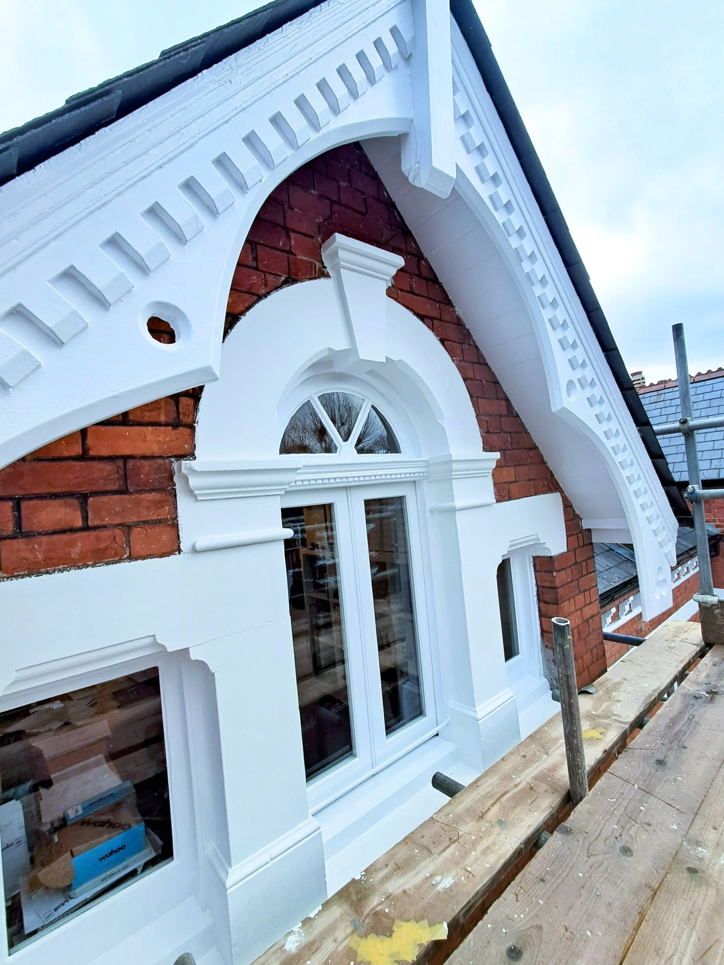 Elegant white facade detailing around a window, showcasing precision painting work