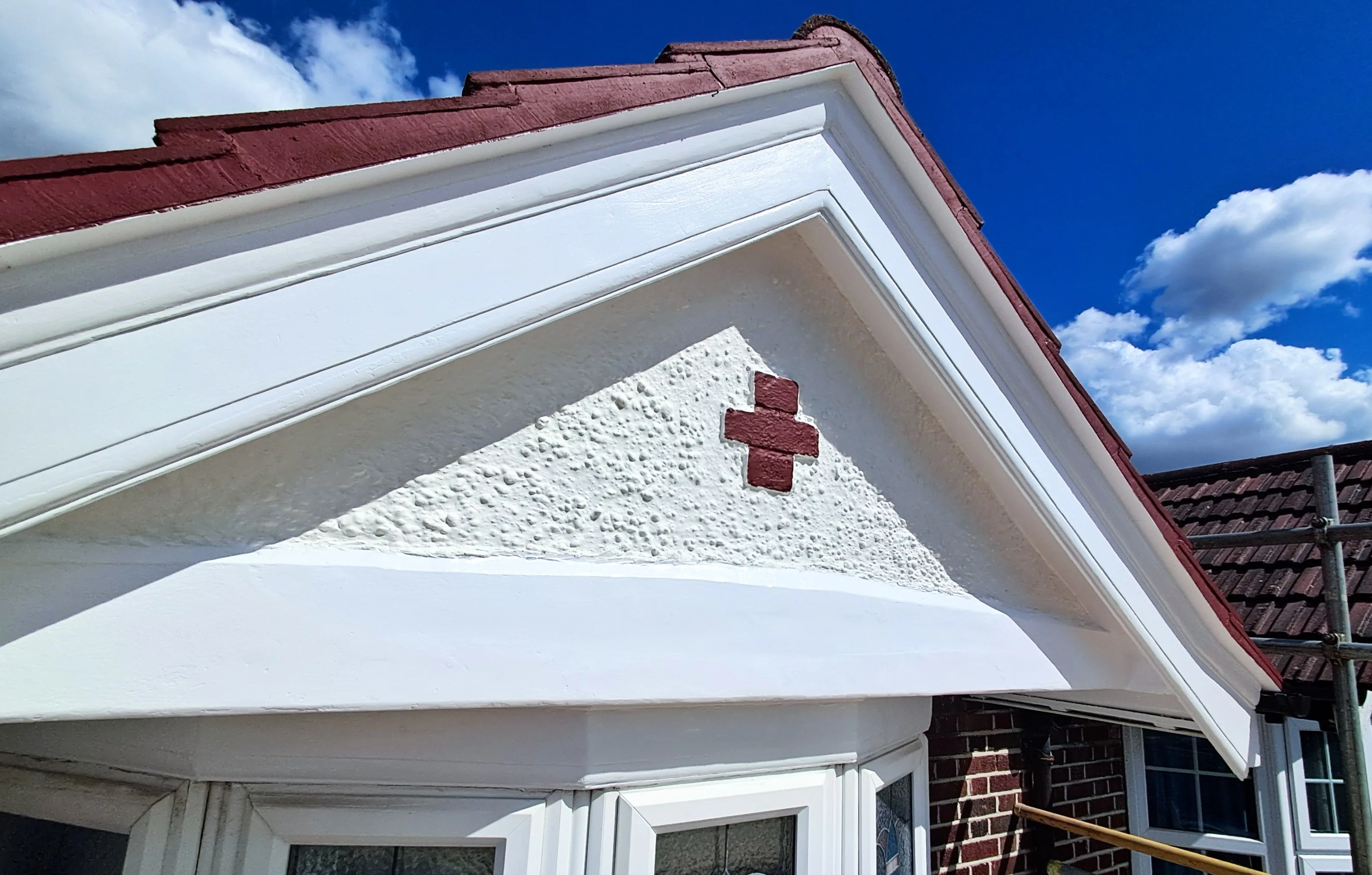Detailed facade painting with red accents and textured finish under blue sky