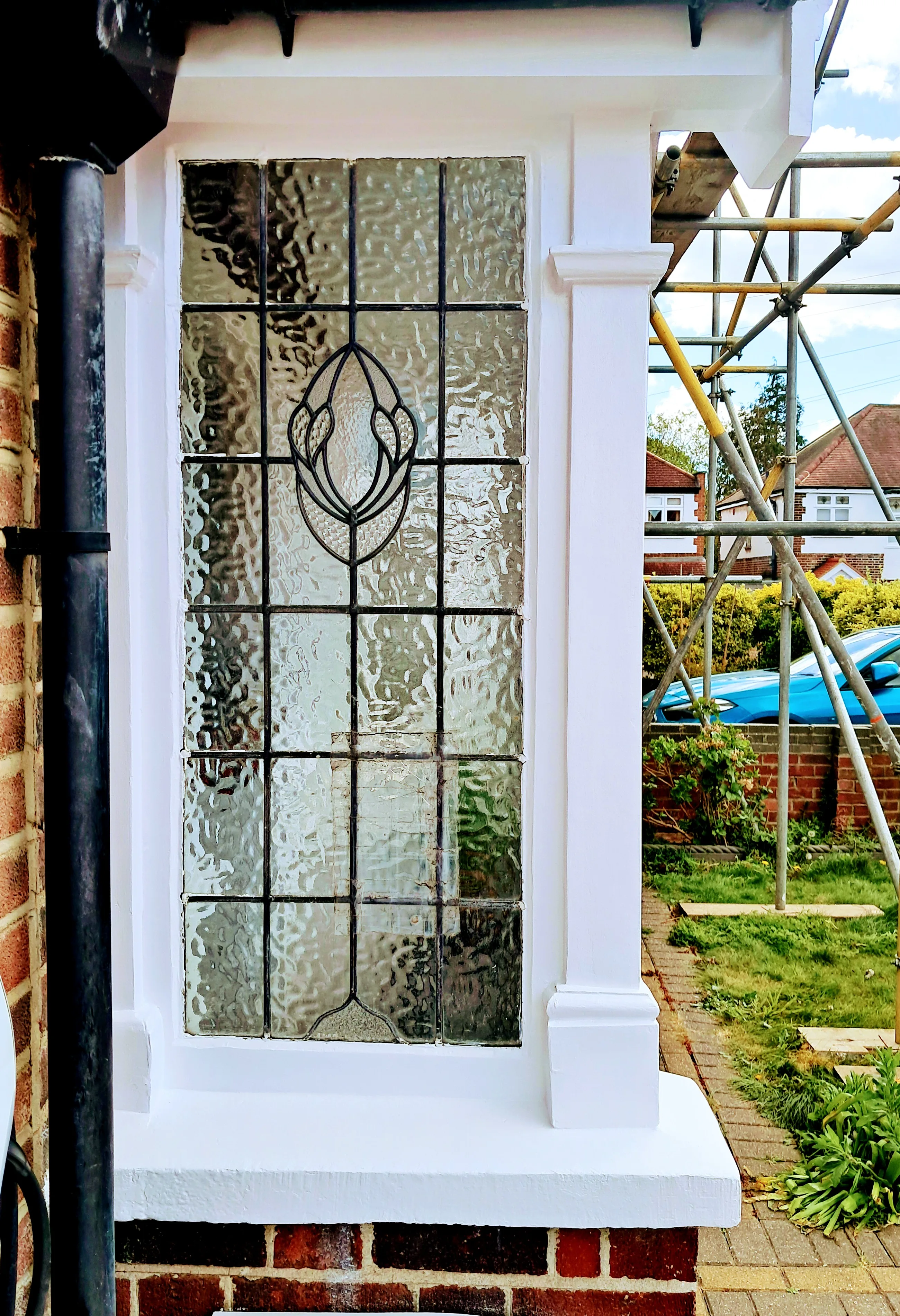 Decorative stained glass window with white woodwork and brick surround