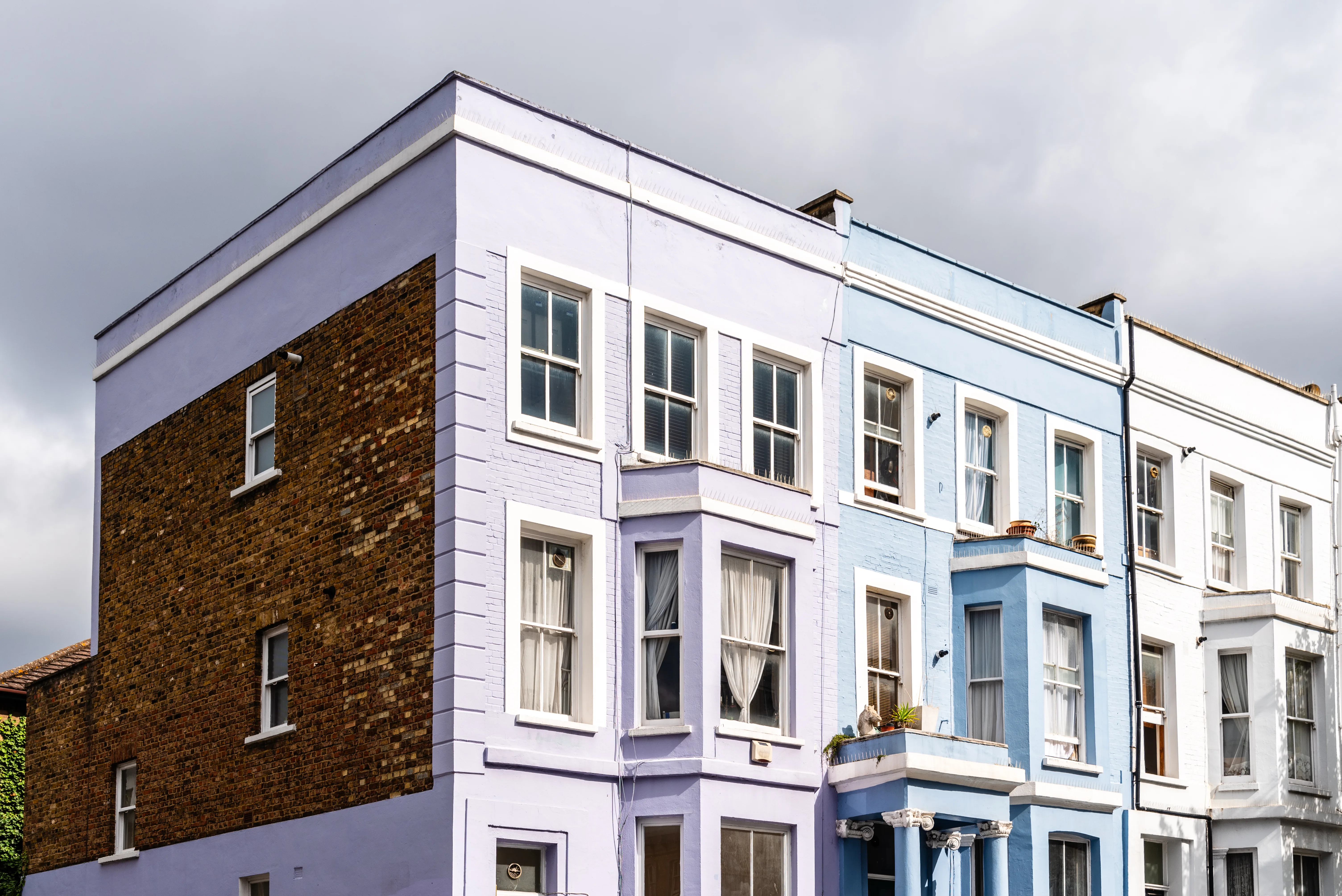 Two residential buildings painted in light purple and blue with decorative details