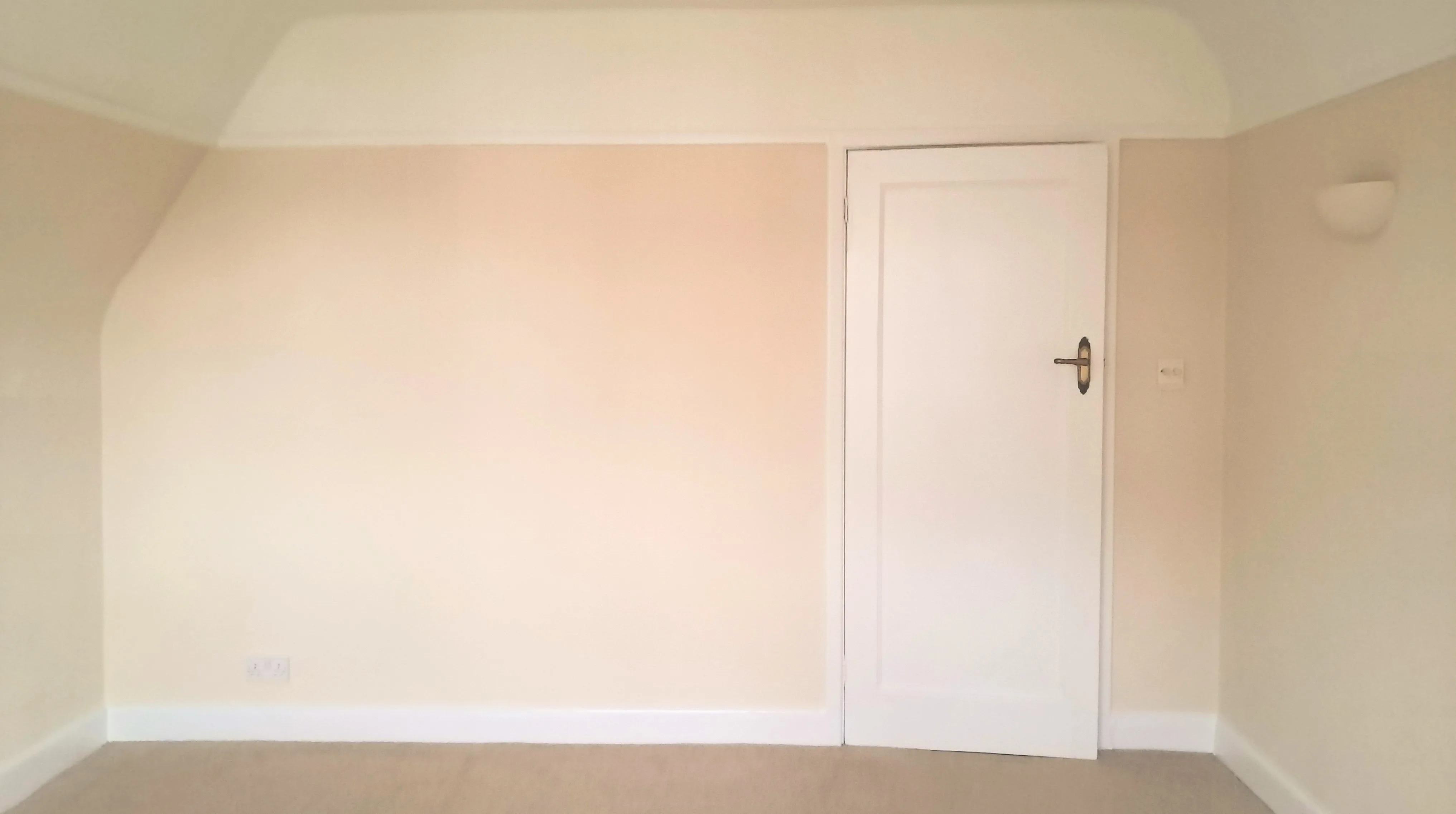 Light-colored interior wall with a door, freshly painted and ready for decorating