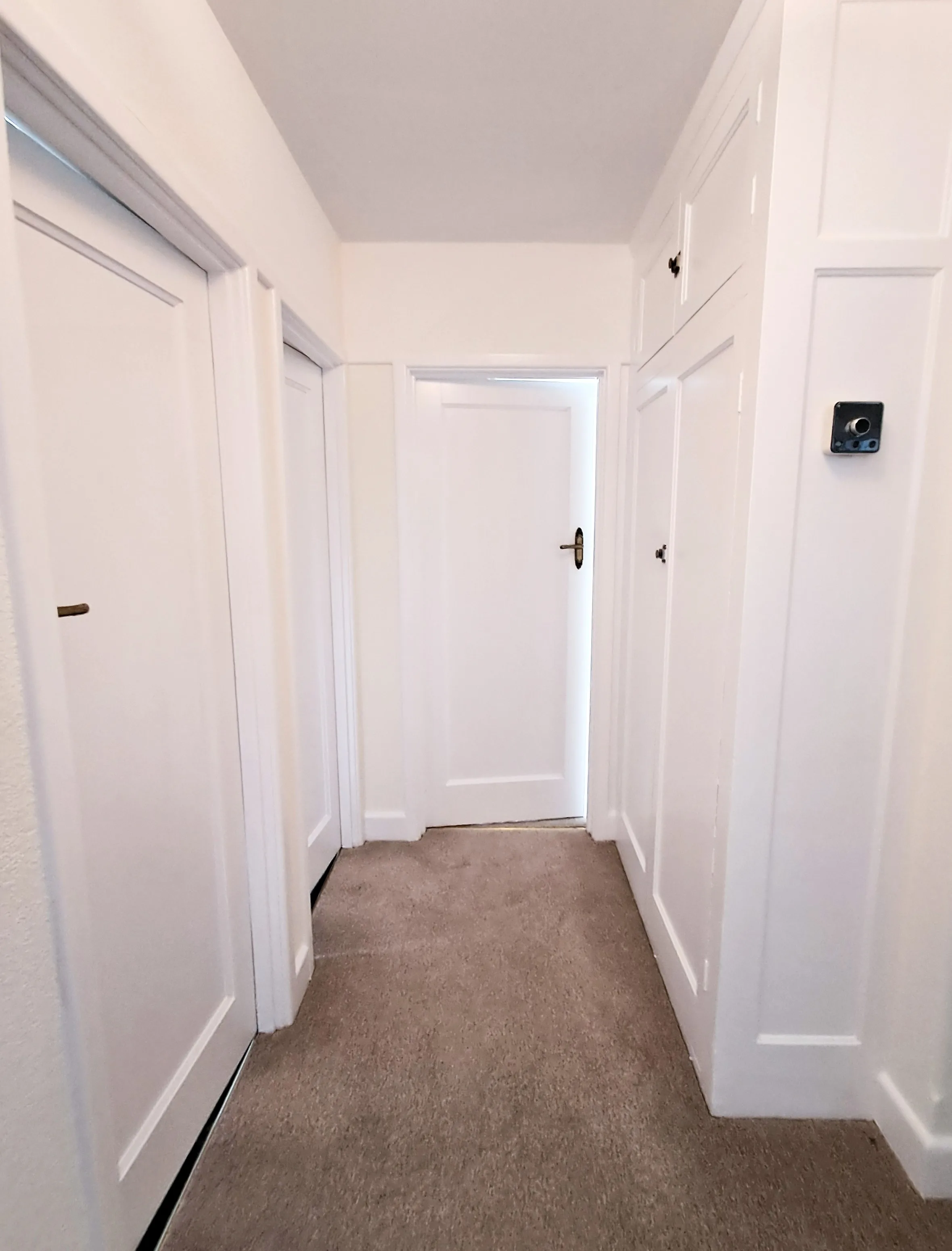 Hallway featuring freshly painted white doors and walls with clean lines