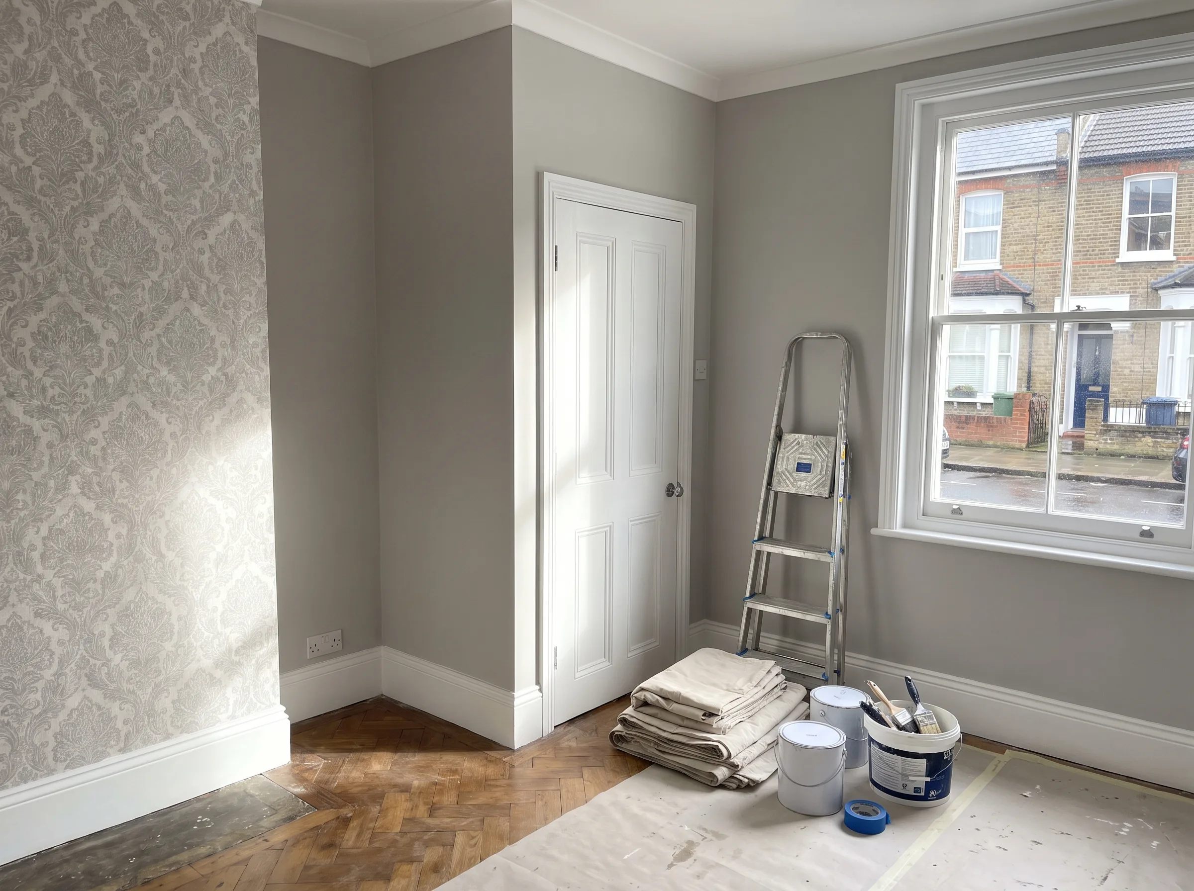 A freshly painted interior room featuring decorative wallpaper and painting supplies