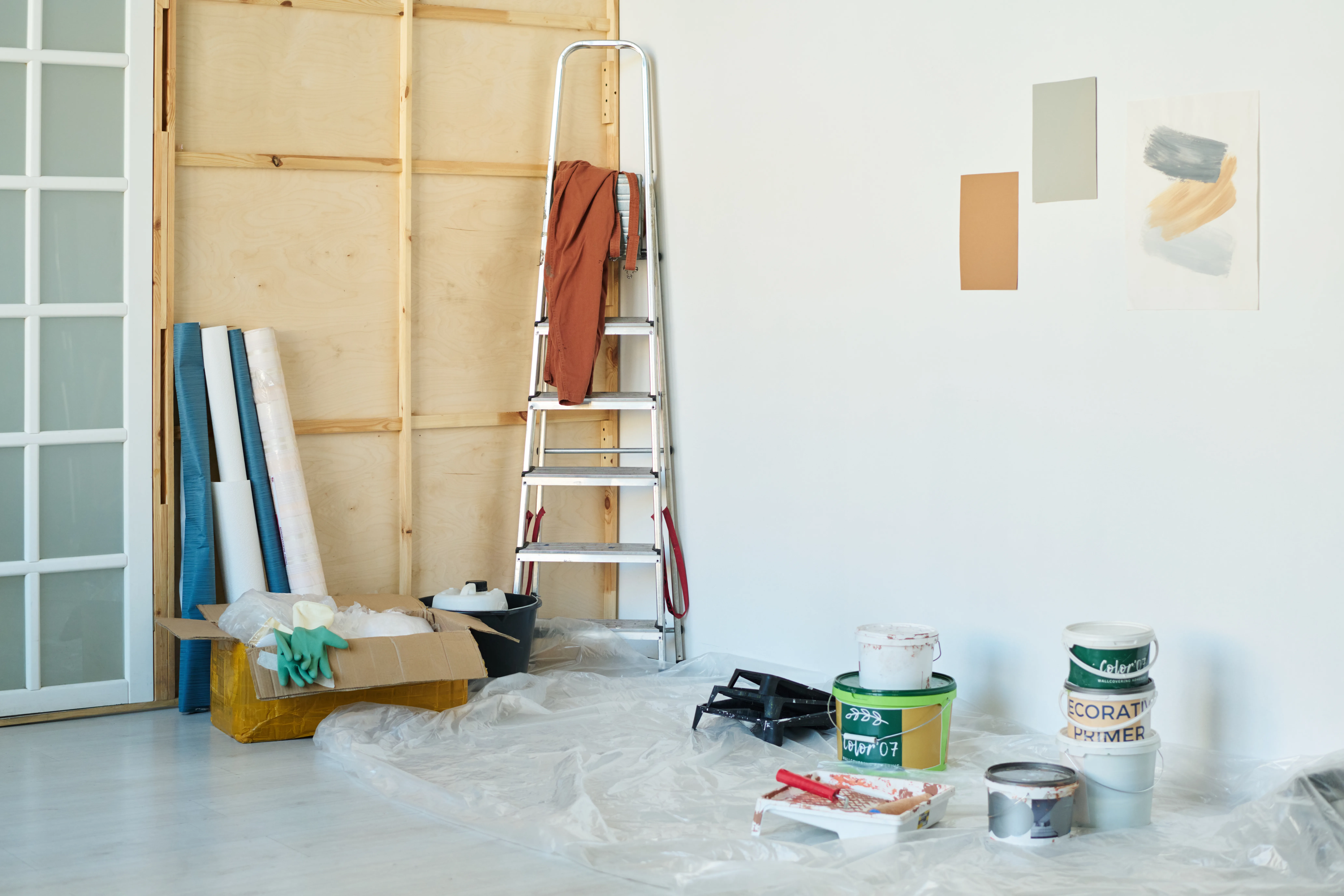 Painting supplies and tools arranged in a room, with color samples on the wall, ready for interior painting services