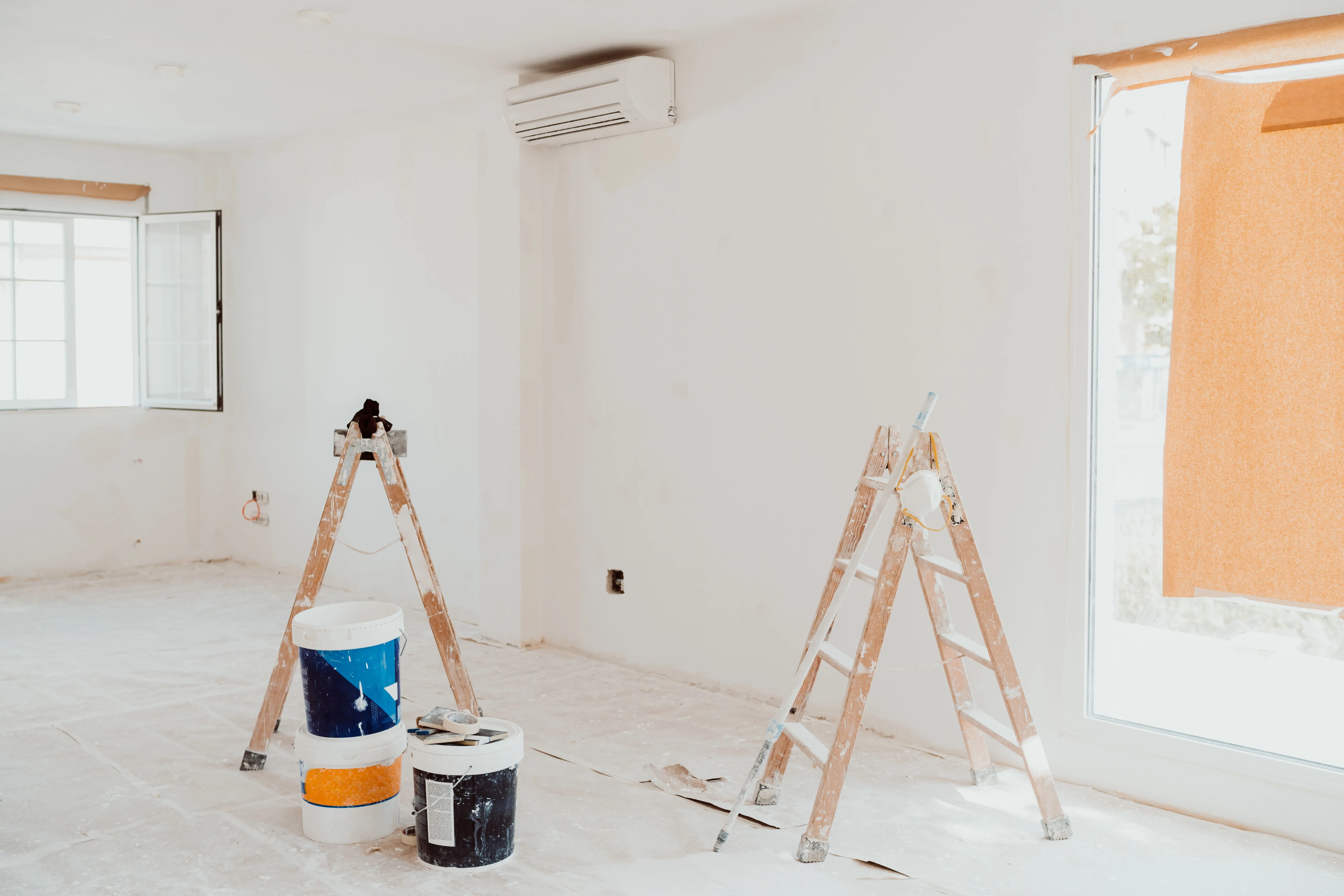 Interior space with ladders and paint buckets, ready for wall painting services