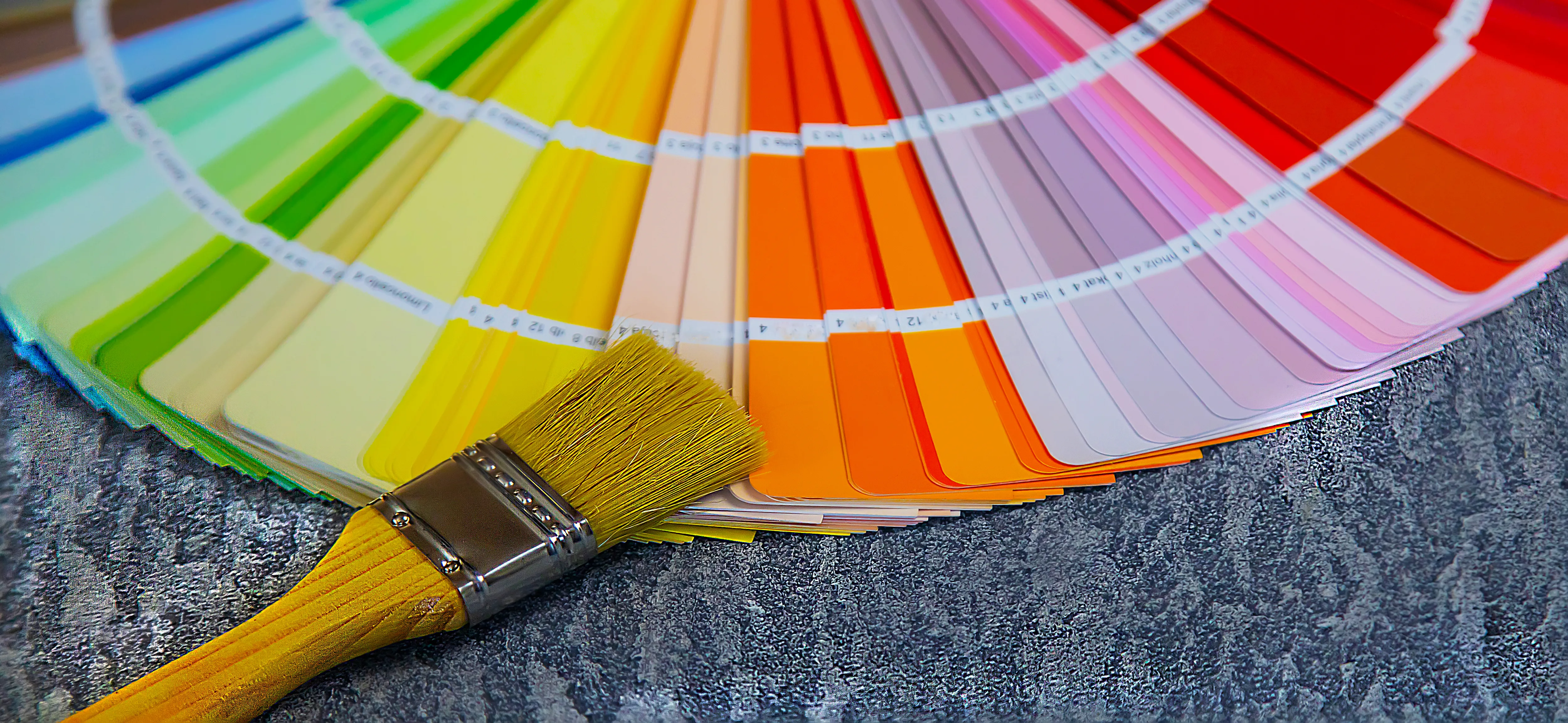 Color swatches fanned out alongside a paintbrush, ideal for interior decorating and painting services