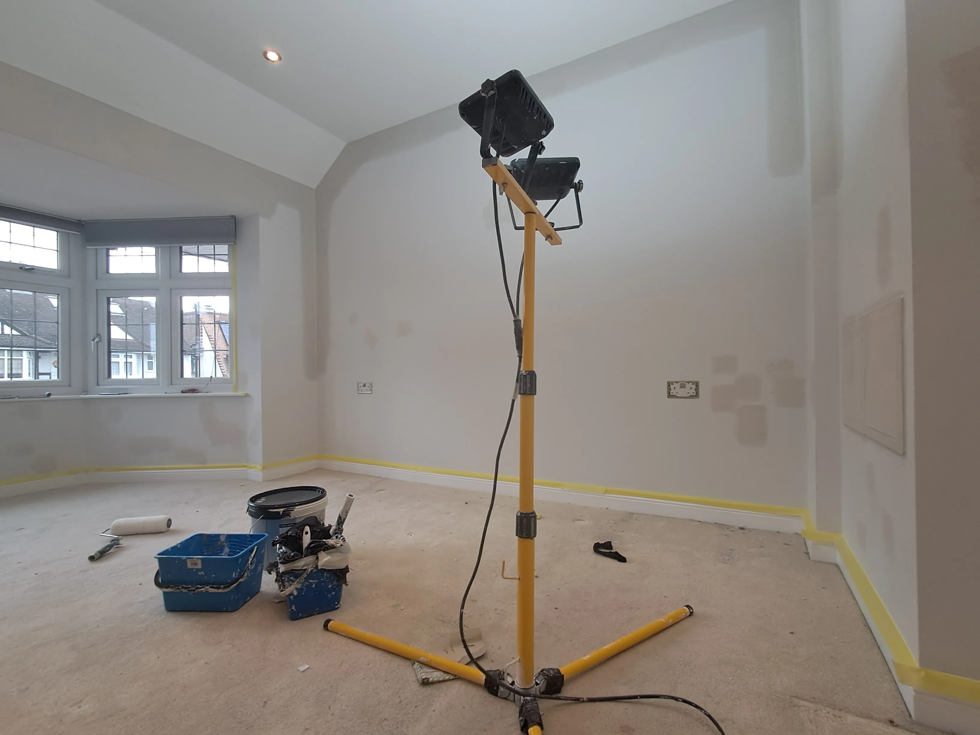 Interior painting setup with a work light and tools in a room ready for painting