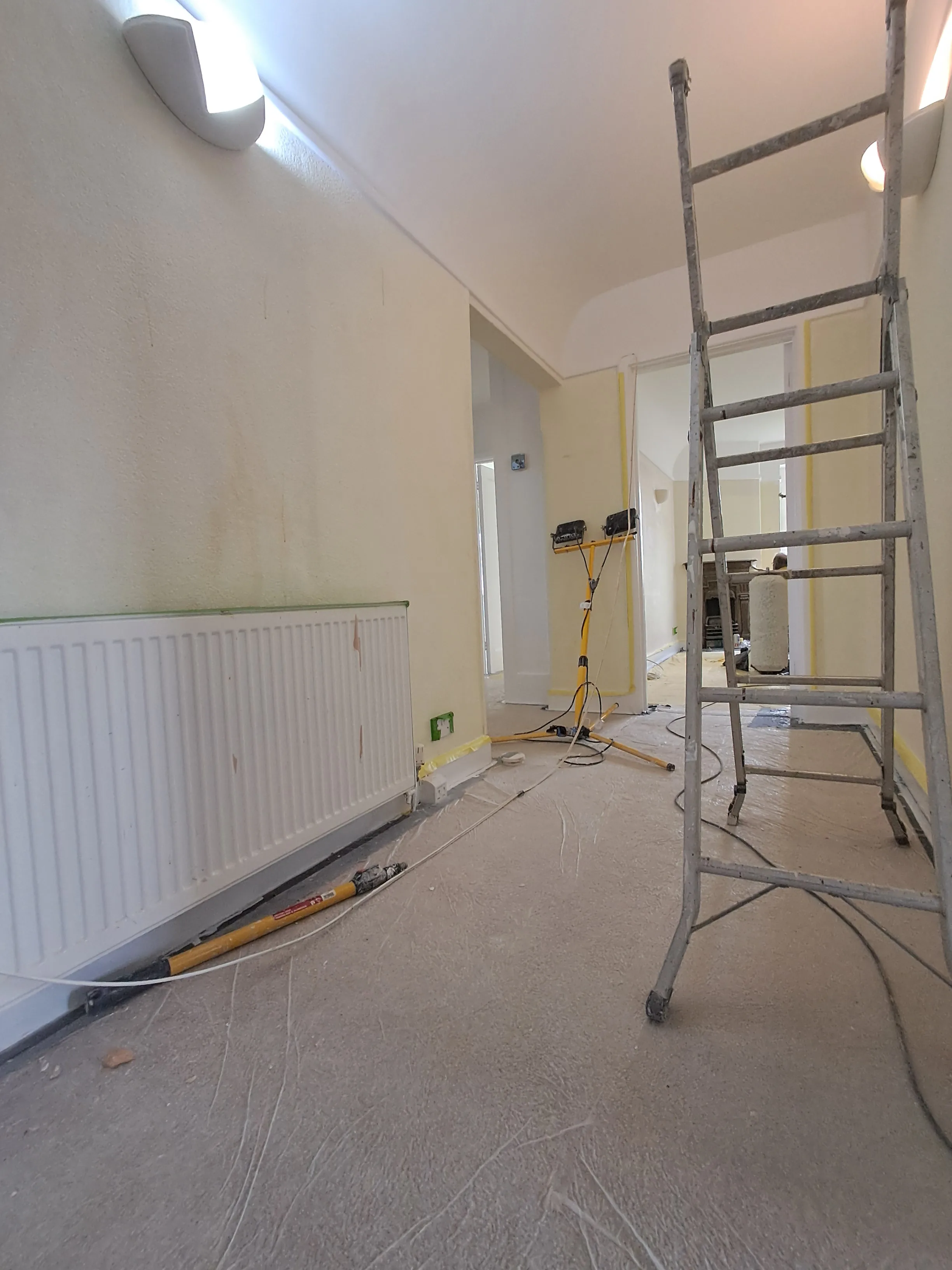 Interior painting in progress, featuring a ladder and tools in a hallway