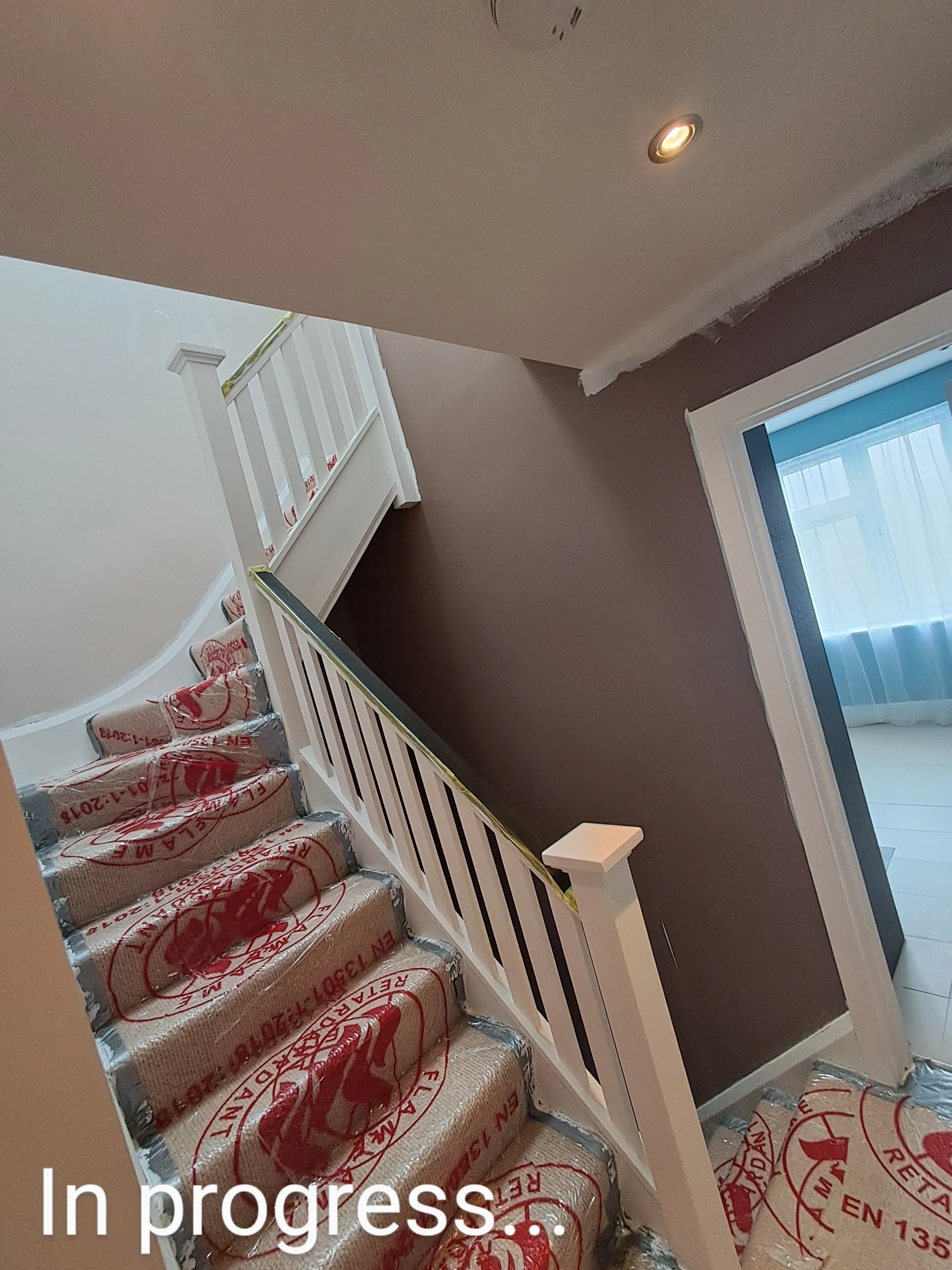 Painting in progress on a staircase with protective covering on steps and walls