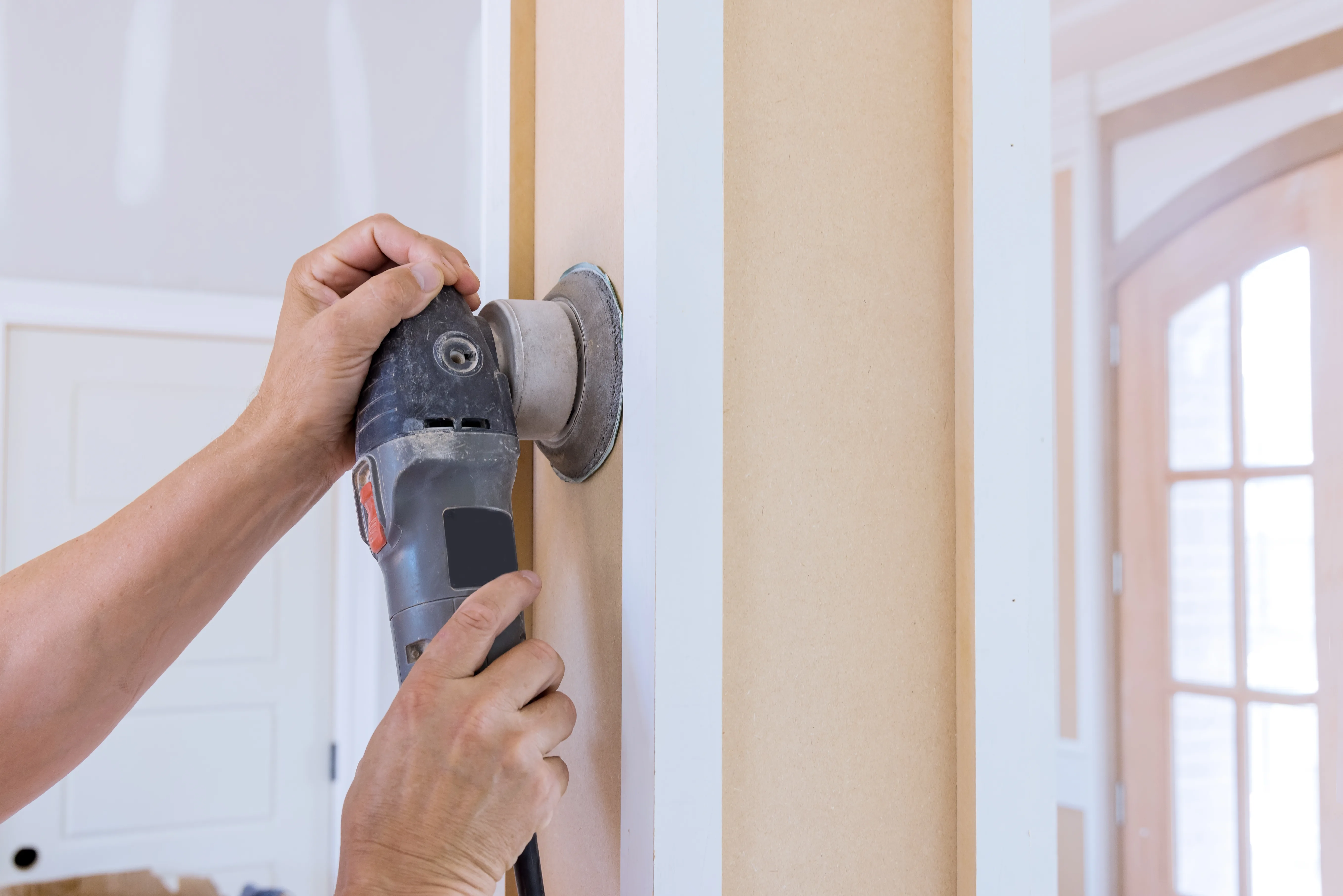 A person using a sander on a wall to prepare for painting services