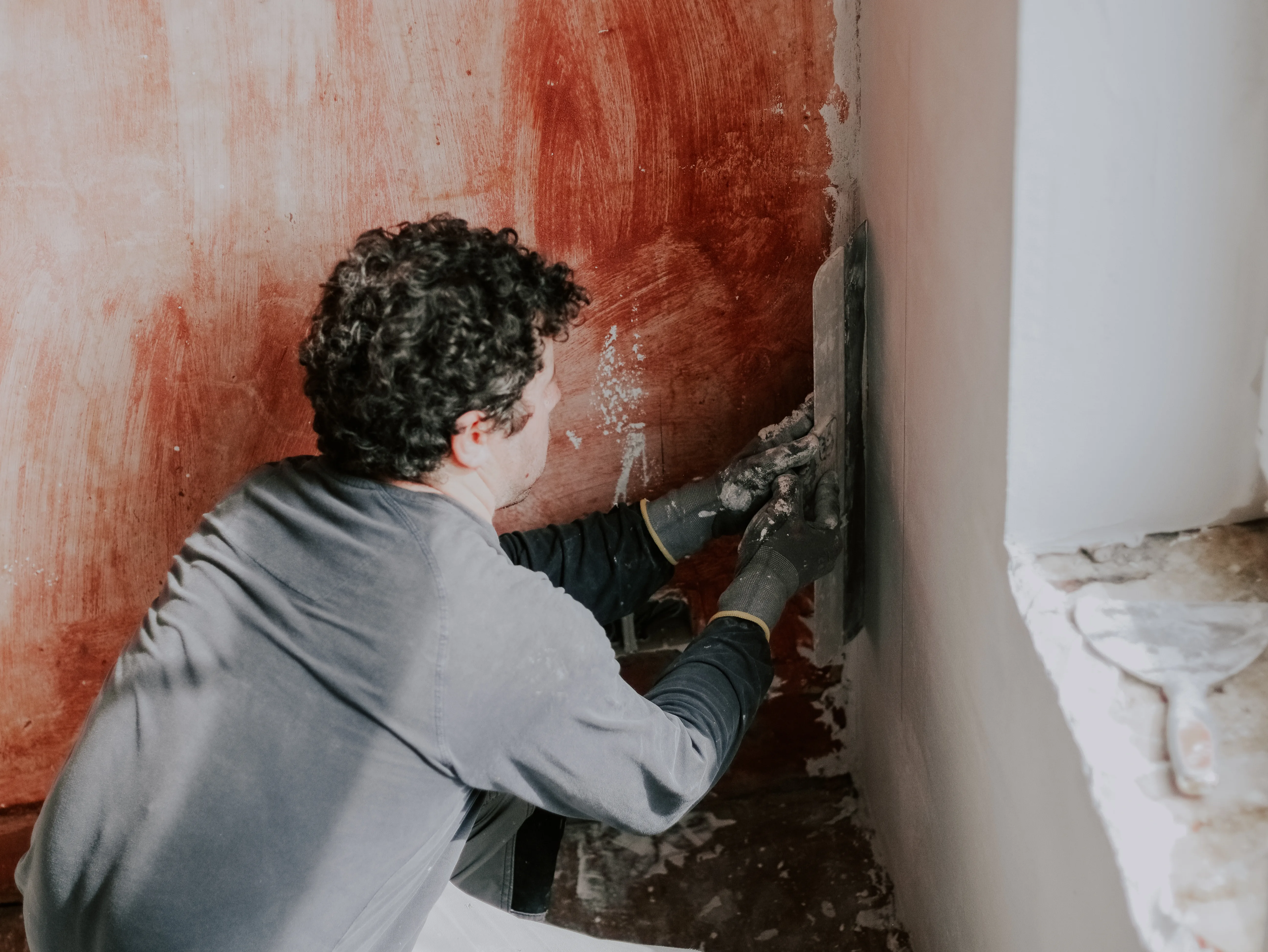 A worker applying plaster to a wall as part of wall repair services