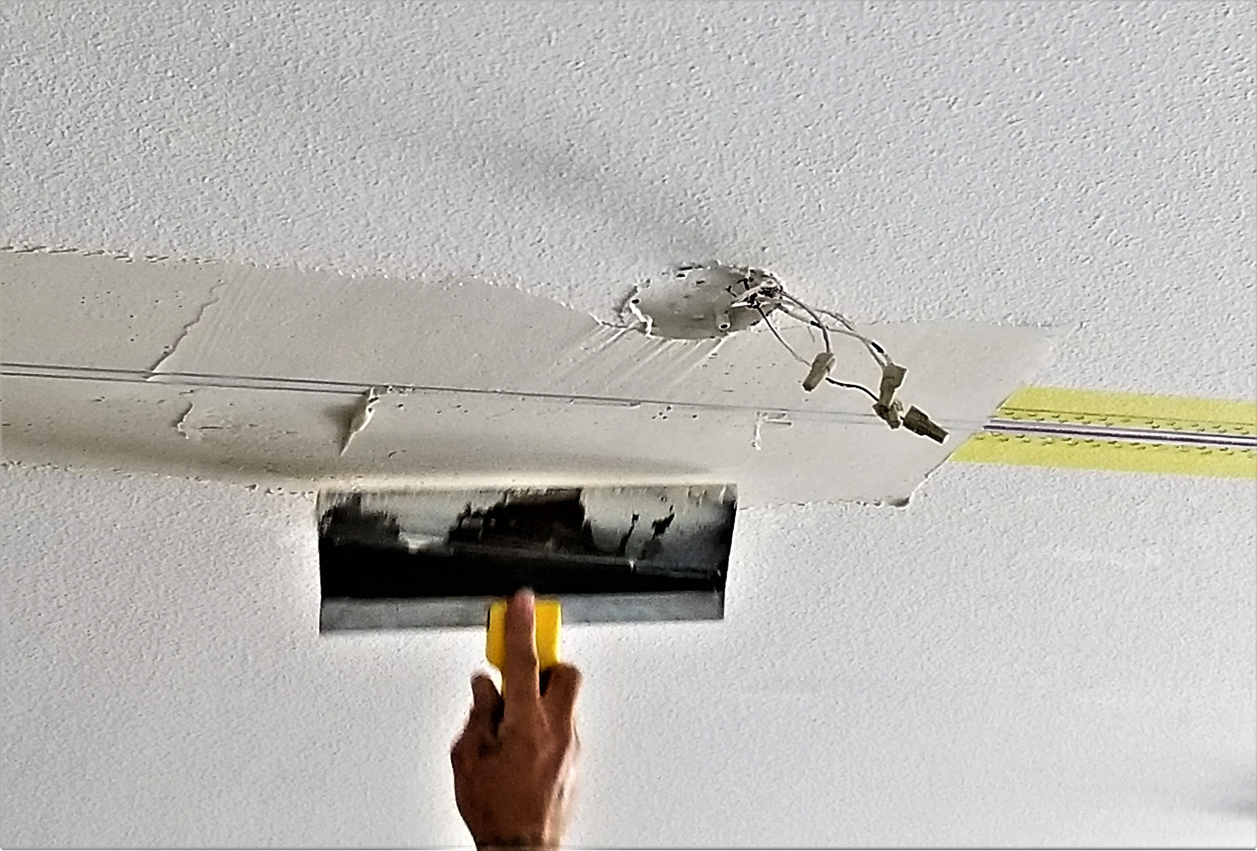 Worker applying finishing touches to a ceiling using a trowel during wall repair